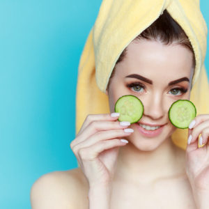 portrait-young-beautiful-woman-with-healthy-skin-holds-two-piece-cucumber-near-face
